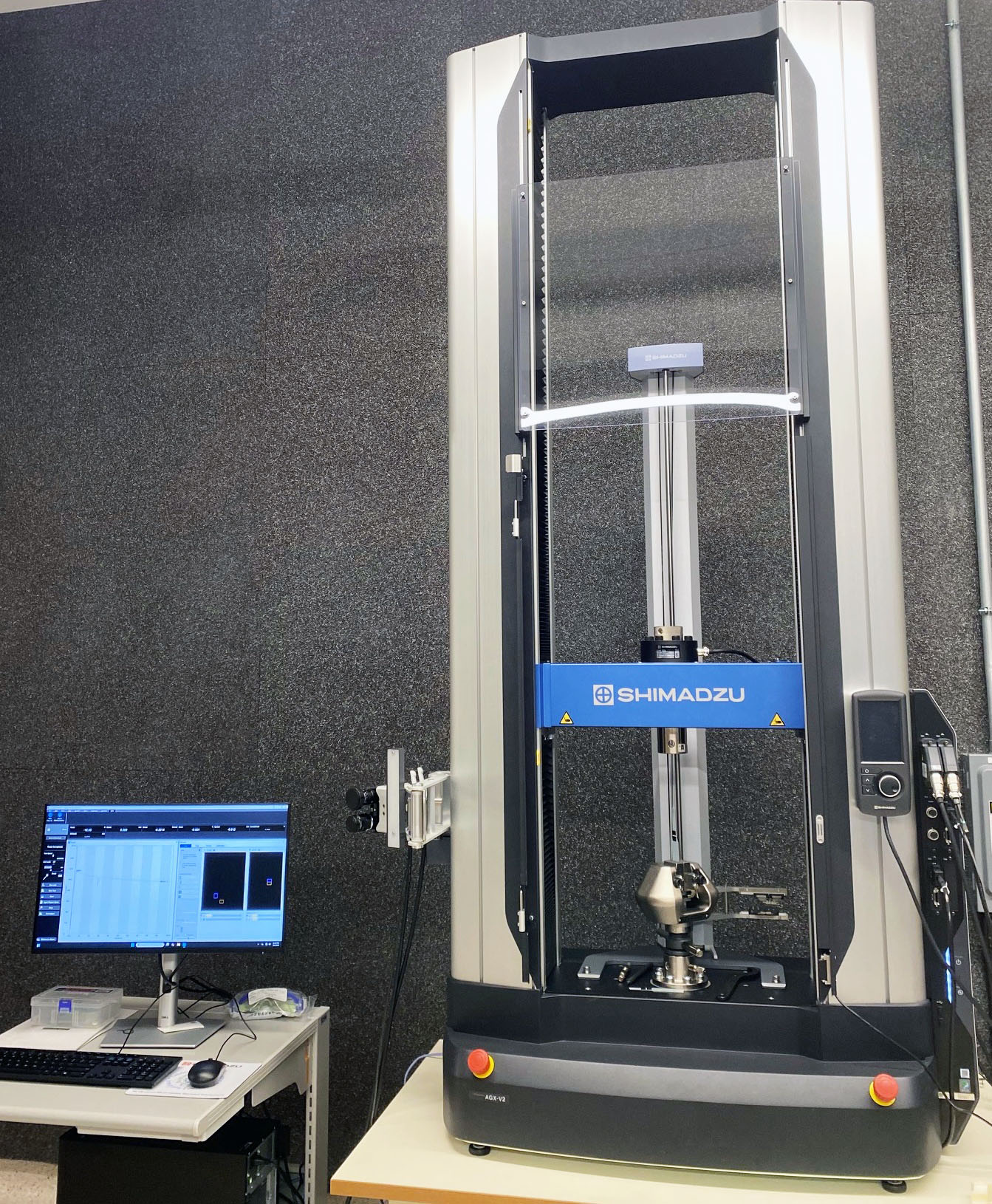 Shimadzu AGX-V2 universal testing system with dual-column test frame, mounted fixture, and connected computer workstation.